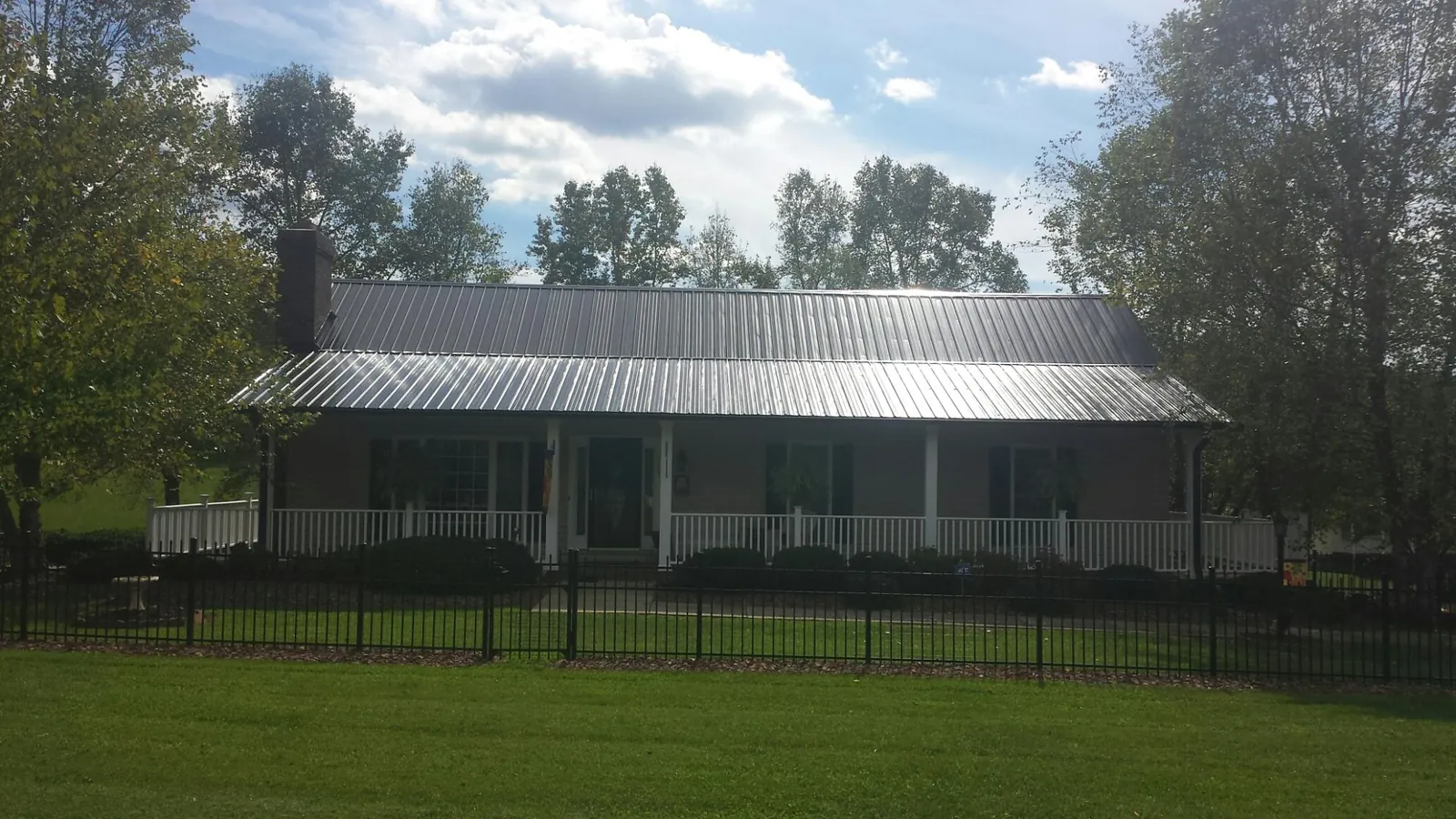 Gray metal roof on a brick ranch with a full width front porch — Gutter Guard Installation work by our crew in Oakville