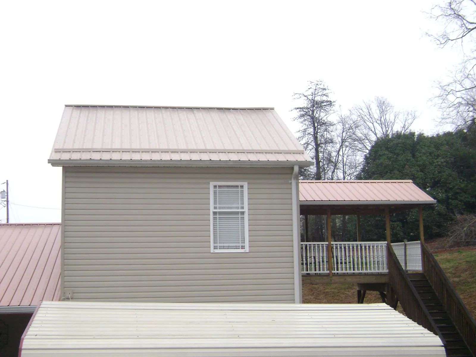 Tan metal roofs on a two story addition and attached porch, from a Roof Replacement job in Oakville