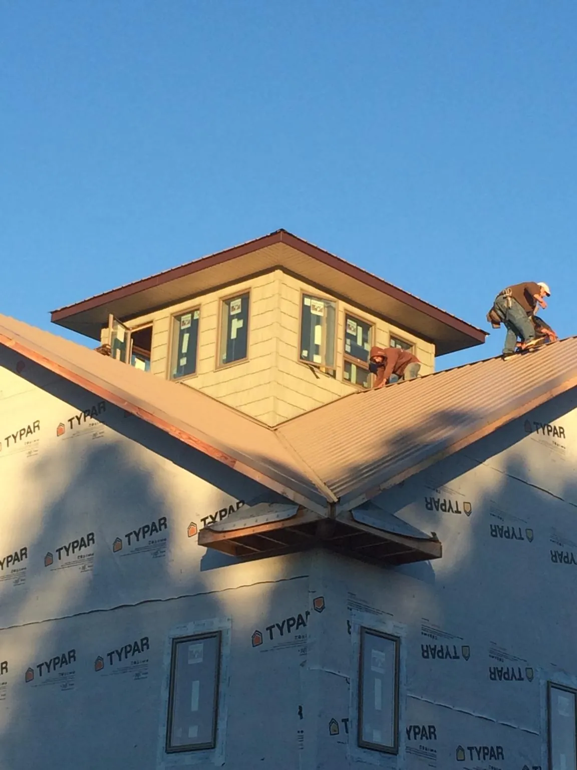 Roofers working around a rooftop cupola on a new metal roof at sunset — Roof Waterproofing in Oakville by Roofing Brothers